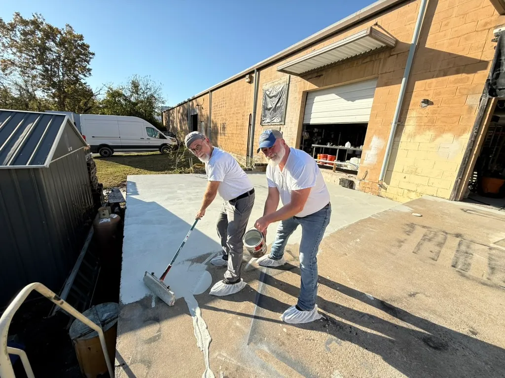 Two People Sealing Concrete Outside Workshop