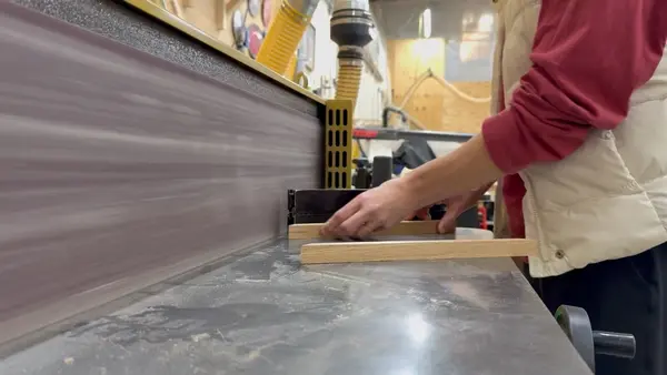 Hands Feeding Wood Through Belt Sander
