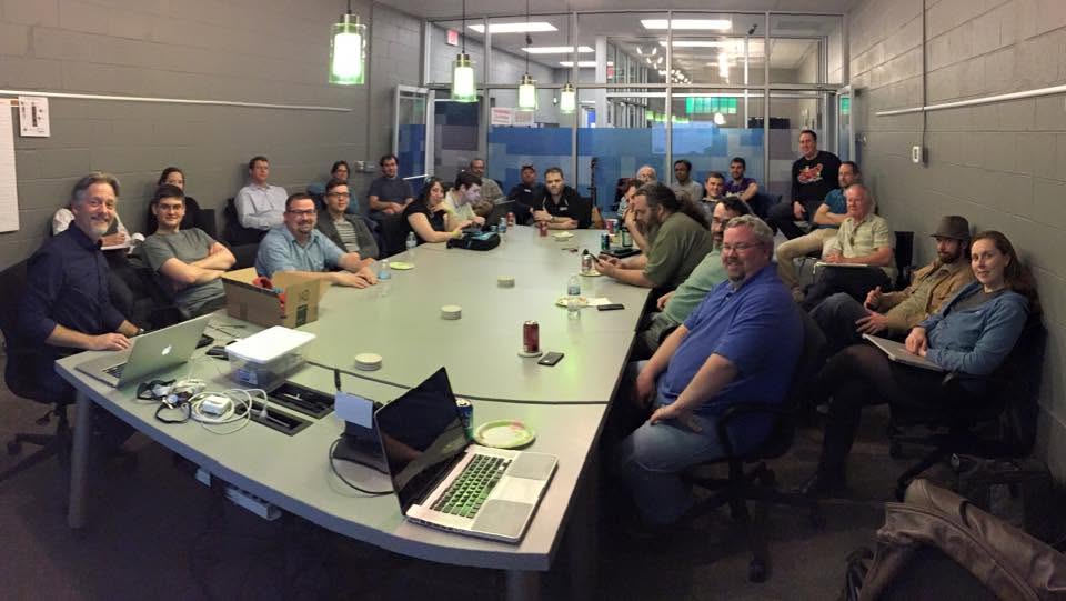 An early Make Nashville meetup, with dozens of makers gathered around a long conference table covered in laptops, cables, and project boxes.