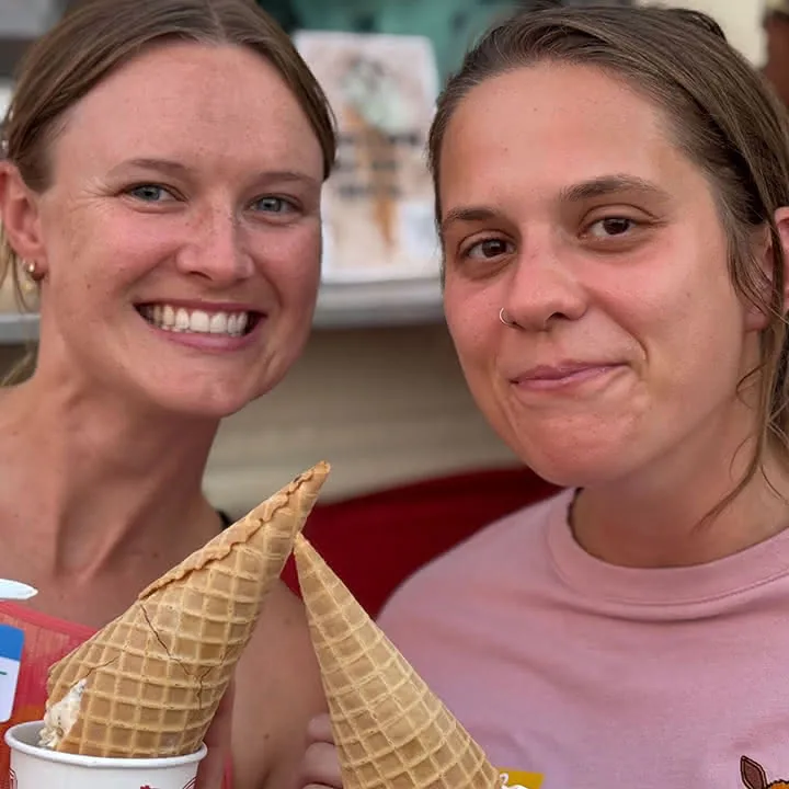 Two people smiling and holding waffle cones with ice cream